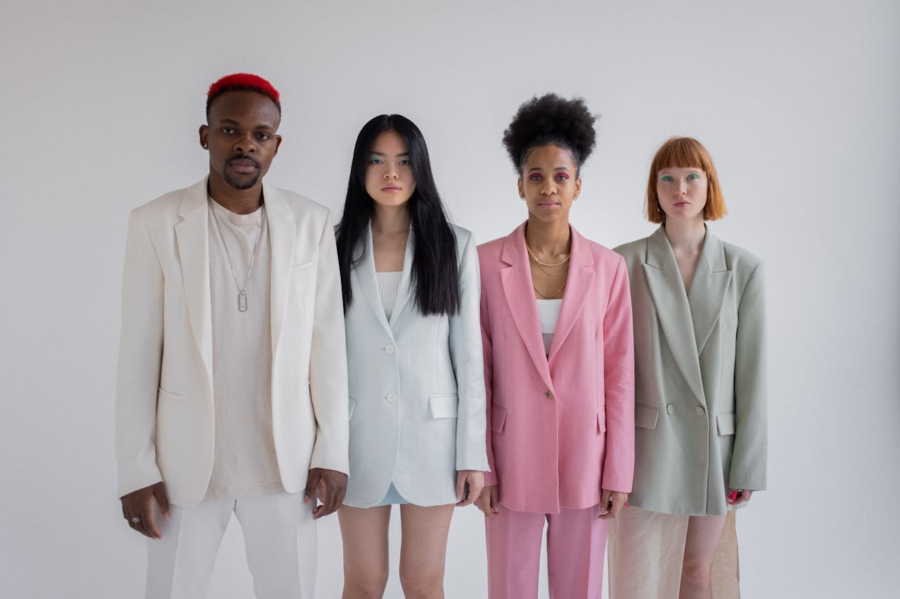 Four diverse young adults in stylish suits posing confidently in a studio.